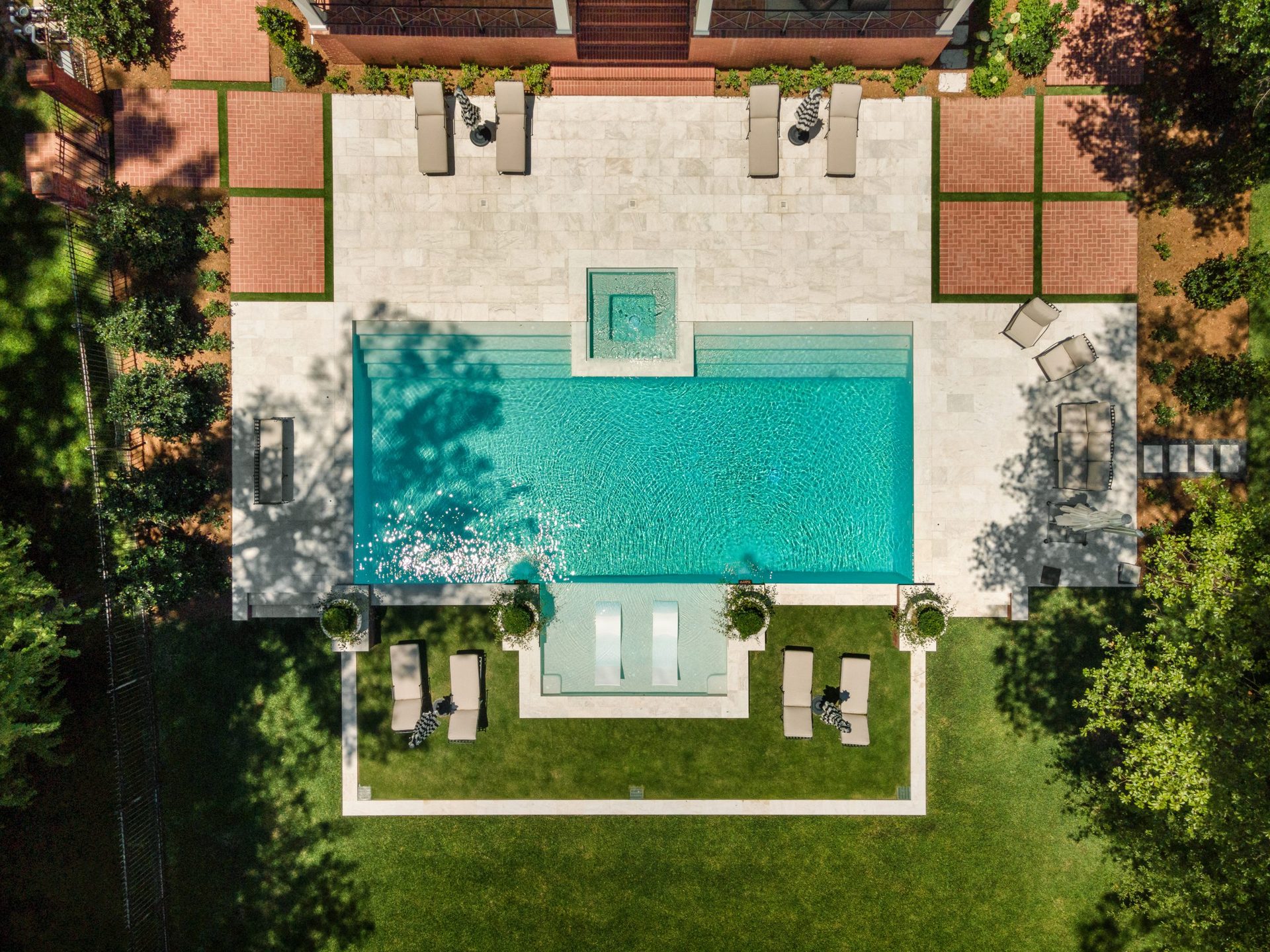 Overhead view of a geometric pool and spa with a travertine lounge deck